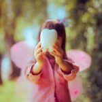 little girl in tooth fairy costume holding a molar toy